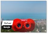 Binocolo a gettoni rosso brillante sulla vista panoramica della città Batumi dalla piattaforma sul tetto sul Mar Nero e cielo blu, magnete per frigorifero